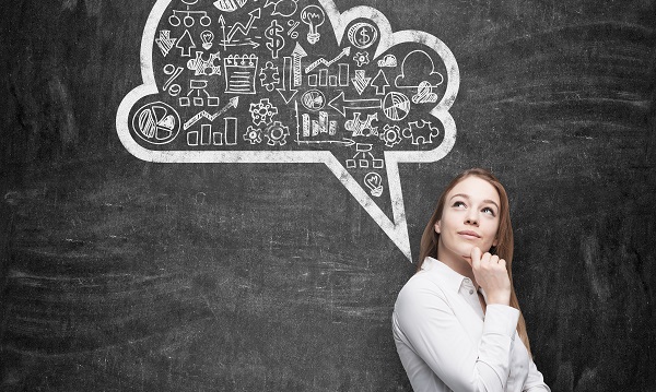 Side view of business lady, student, who is thinking about new business concepts. Drawn cloud with business icons on the black chalkboard.